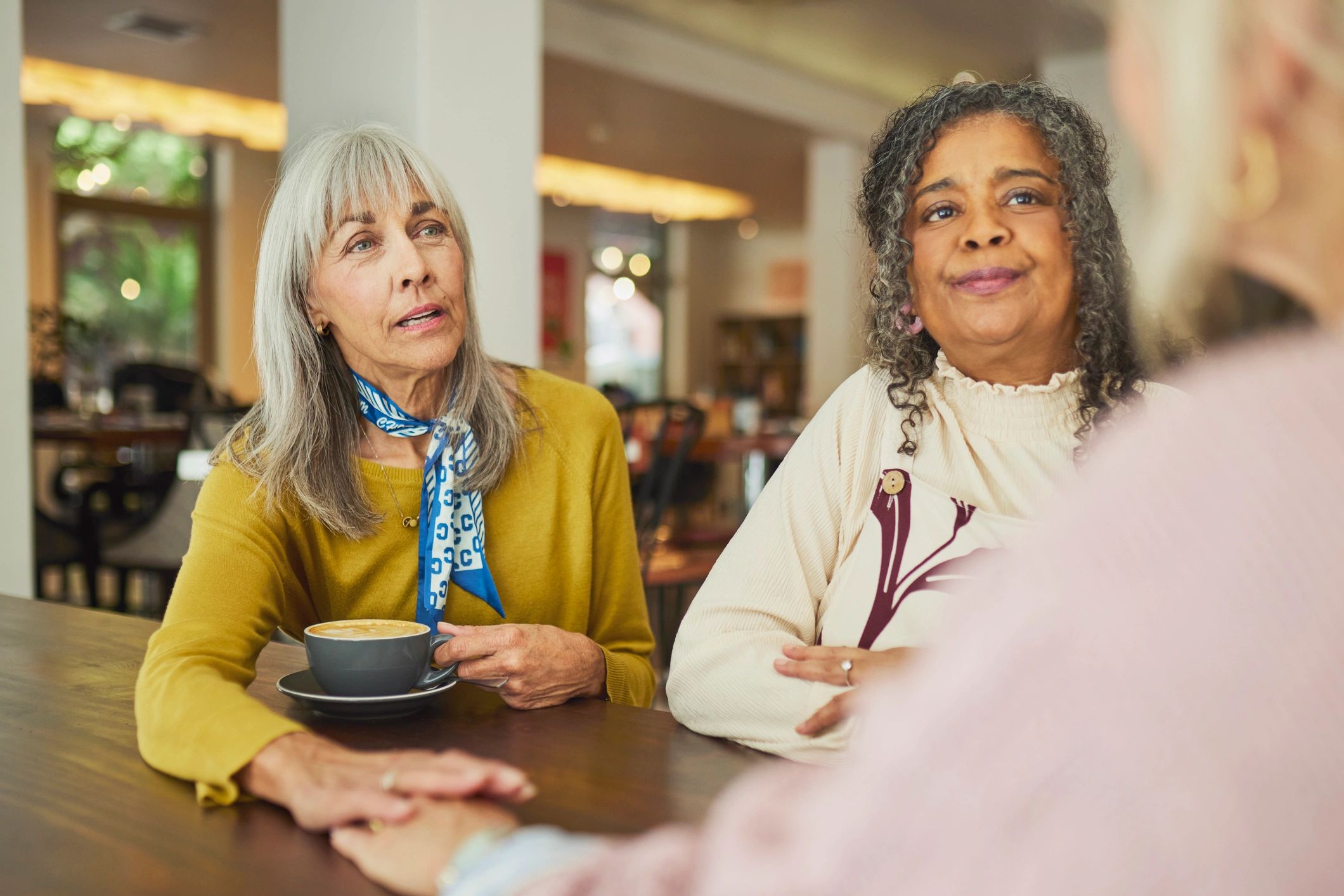 Two senior women having a thoughtful conversation at a cafe